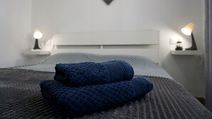 A neatly made bed with a blue blanket, two bedside tables with lamps, and a heart-shaped decoration on the wall.