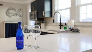 Eine Küche mit Marmorarbeitsplatte, einer blauen Wasserflasche und zwei Weingläsern.