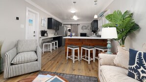 Eine moderne Küche mit Barhocker, einem gestreiften Sofa und einer großen Pflanze.