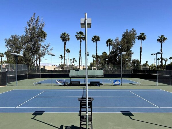 Cancha de tenis con red, bancos y un letrero que dice Pro Penn.