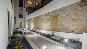 A modern indoor corridor with a stone wall, recessed lighting, and a tiled floor. - Courtyard Oporto Design Apartment D (Porto)