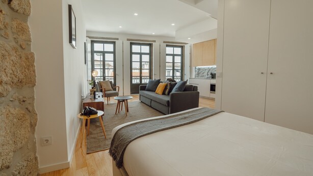 A modern bedroom with a large bed, a sofa, a small table, and a wardrobe. - Courtyard Oporto Design Apartment D (Porto)