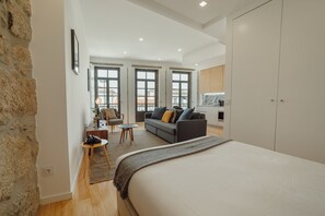 Une chambre moderne avec un grand lit, un canapé, une petite table et une armoire.