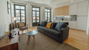 A modern living room with a sofa, a dining table, and a kitchen area with cabinets. - Courtyard Oporto Design Apartment D (Porto)