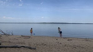 A beach with two people fishing by the water.