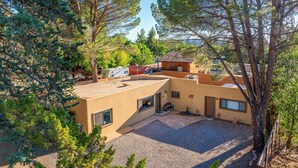 Une maison moderne dotée d’un vaste patio, entourée d’arbres.