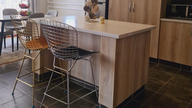 Une cuisine moderne dotée d’un îlot central, de meubles en bois et d’un four à micro-ondes encastré.