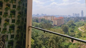 Une pièce avec vue sur le paysage urbain, une rambarde de balcon et un luminaire suspendu.