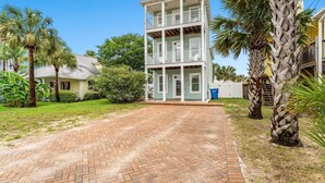 A two-story building with a brick driveway and palm trees. - Panama City Beach House with Heated Private Pool, Gulf Views, & Steps to Beach! (Panama City Beach)