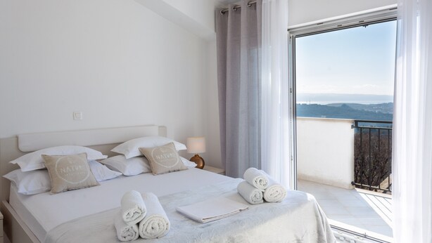 A hotel room with a bed, pillows, a nightstand, a lamp, and a view of the outdoors. - Villa Melki SAVE 20 percent on Split-villas com (Klis)