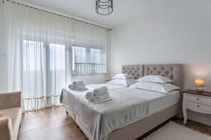 Quarto bem organizado com uma cama grande, mesa de cabeceira com abajur e uma cadeira.
