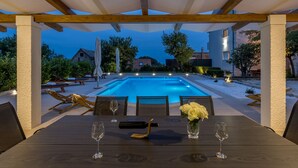 A poolside dining area with a view of a swimming pool, outdoor seating, and a pergola structure. - Villa Melki SAVE 20 percent on Split-villas com (Klis)