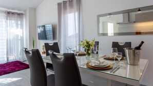 A modern dining area with a glass table, dark chairs, and a wine bottle in a metal bucket. - Villa Melki SAVE 20 percent on Split-villas com (Klis)
