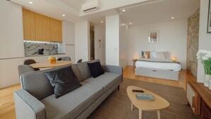 Una sala moderna con un sofá gris, una mesa de centro y una cama con una mesita de noche.