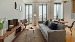 Una sala moderna con sofá, televisor y comedor con mesa y sillas.