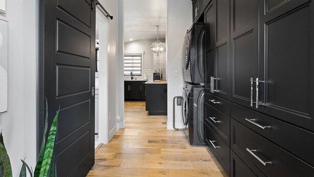 A modern kitchen with dark cabinetry, a central island, and a visible washing machine. - Pikes Retreat - Mountain Views + Modern Comfort - Hot tub (Colorado Springs)