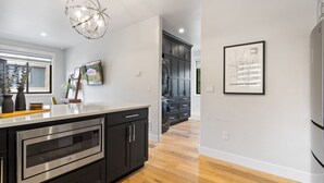 A modern kitchen with a built-in microwave, dark cabinetry, and a wooden floor. - Pikes Retreat - Mountain Views + Modern Comfort - Hot tub (Colorado Springs)