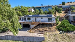 A residential building with a flat roof, a covered outdoor deck, and a staircase leading to a garage.