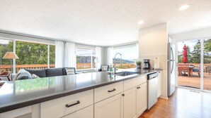 A modern kitchen with a large island, white cabinetry, and a view of the outdoors.