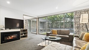 A modern living room with a fireplace, a flat-screen TV, a sofa, and a coffee table. - CENTRAL LOCATION - CONTEMPORARY 2 BEDROOM APTM (Queenstown)