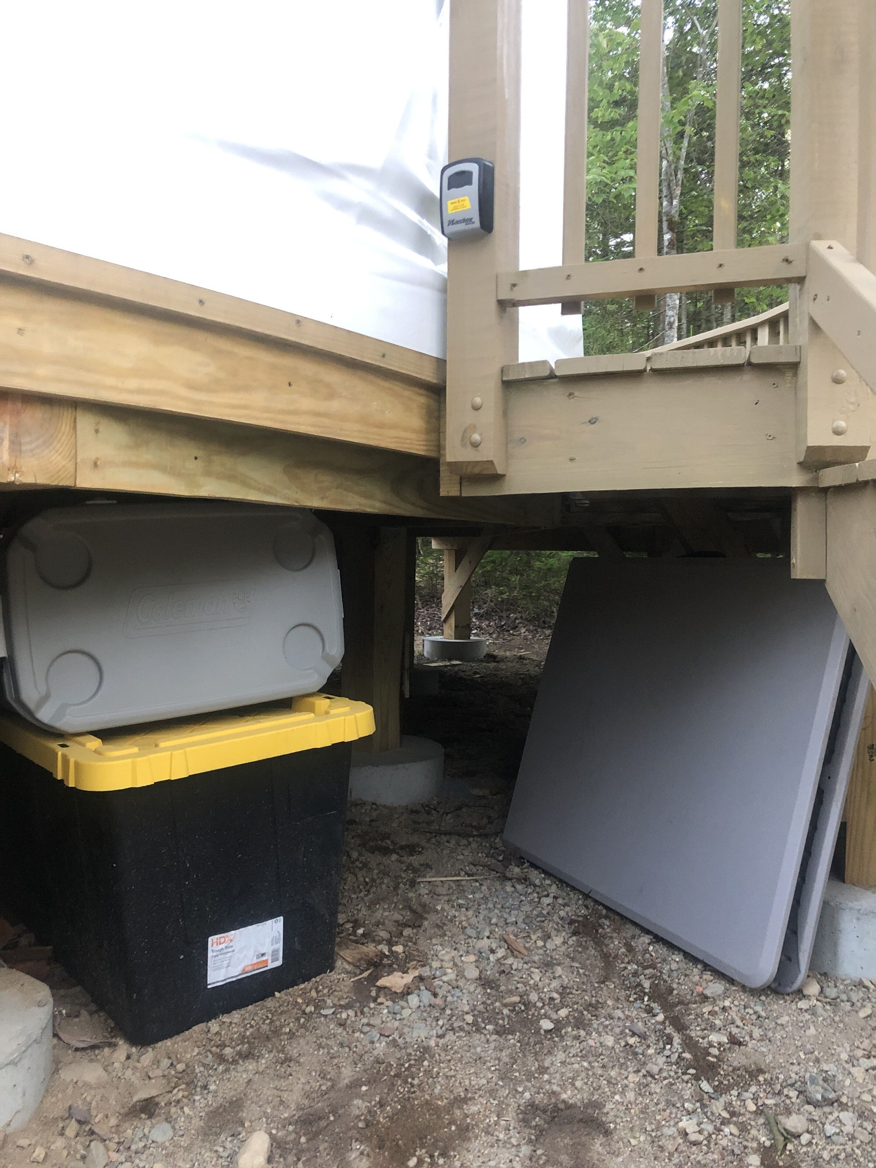 En byggarbetsplats med en träkonstruktion, en svart container och en stor grå panel.