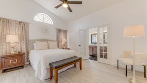 A bedroom with a bed, bedside tables, a bench, a ceiling fan, a window, curtains, a mirror, and a door leading to another room. - Scottsdale Resort Getaway!! Newly Renovated!! (Scottsdale)