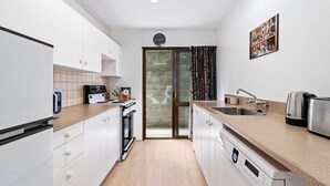A modern kitchen with white cabinets, a wooden countertop, a built-in oven, a dishwasher, a sink, and a clock on the wall. - TOWN CENTRE LOCATION WITH STUNNING VIEW - UNIT 8 (Queenstown)