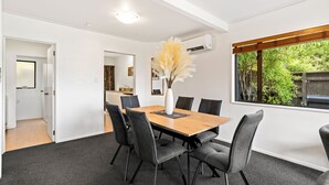 A modern dining area with a wooden table, six grey upholstered chairs, and a vase with pampas grass. - TOWN CENTRE LOCATION WITH STUNNING VIEW - UNIT 8 (Queenstown)