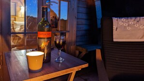 Pullo [yellow tail] -merlot-viiniä, lasi viiniä ja keltainen muki puisella pöydällä ikkunan vieressä.
