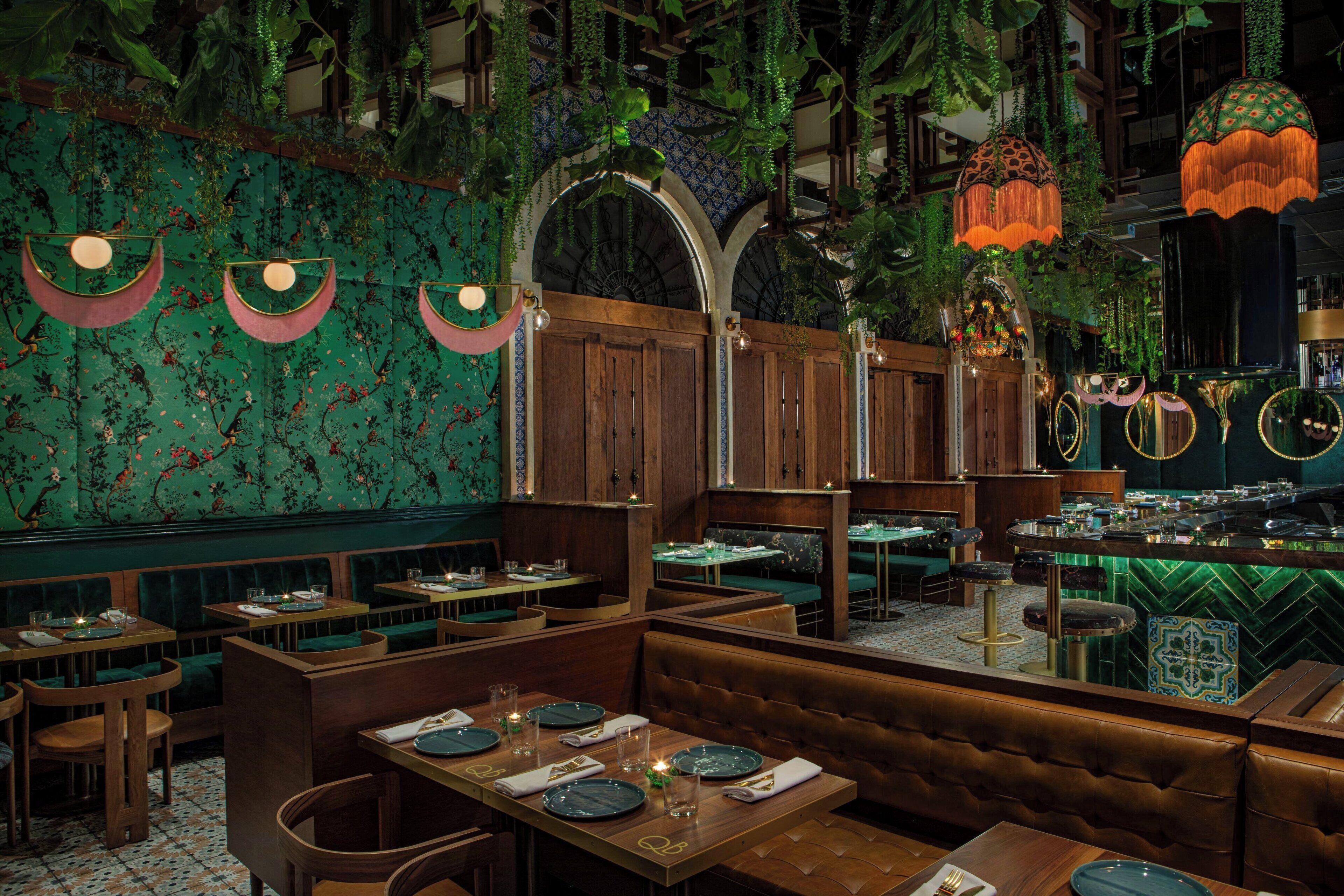 A restaurant with booths, tables, and hanging plants.