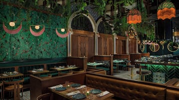 A restaurant with booths, tables, and hanging plants.