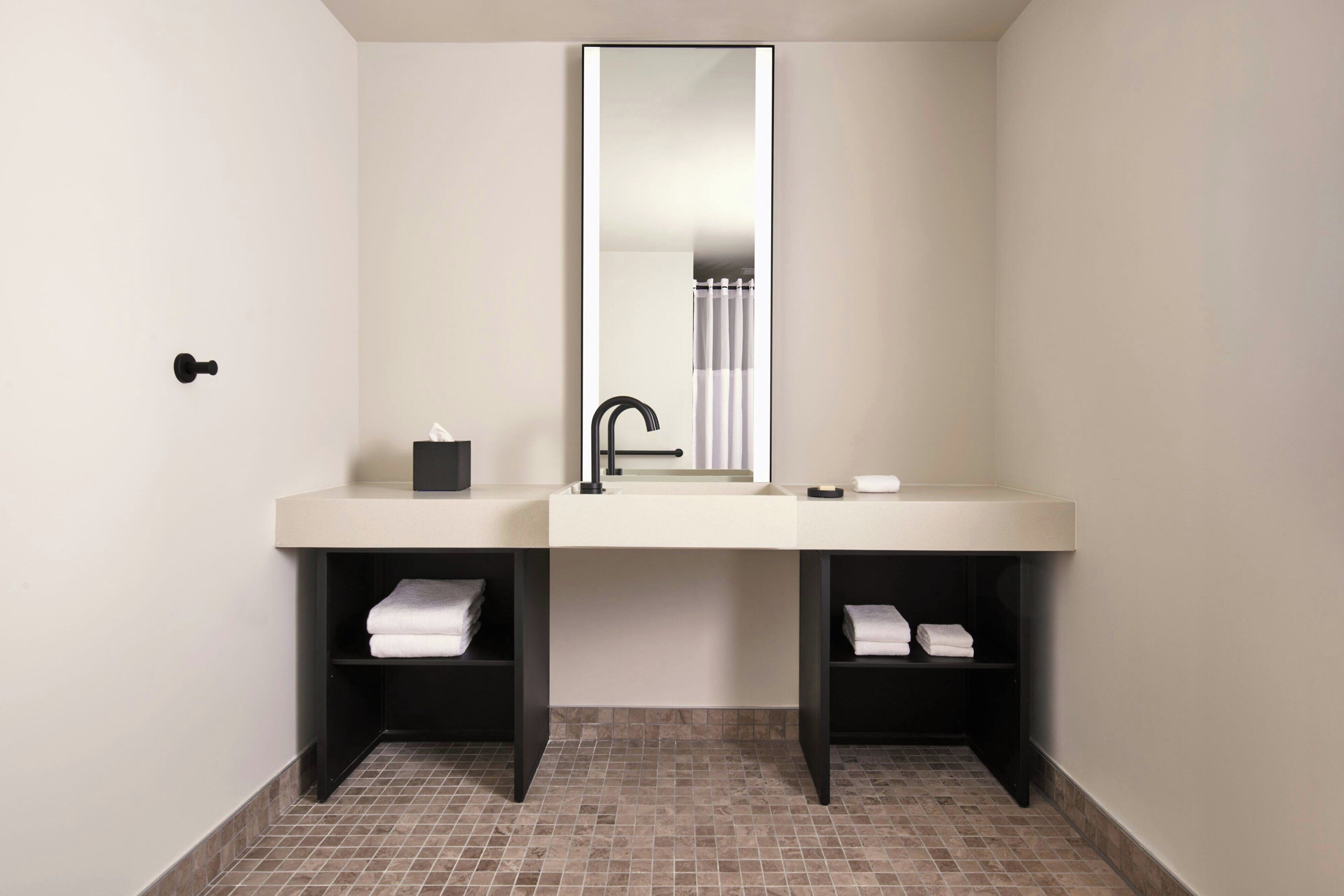 A modern bathroom with a double sink, a large mirror, and two towel racks.
