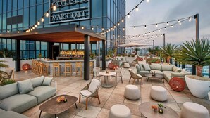 A rooftop bar area with seating, a bar, and a view of the cityscape. - AC Hotel Downtown Los Angeles, a Marriott Hotel (Los Angeles)