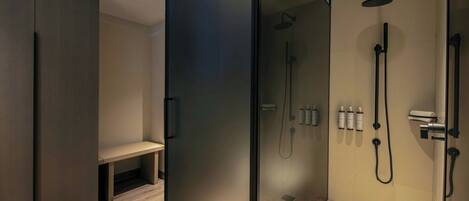 A modern bathroom with a glass shower enclosure, a bench, and a wooden floor.