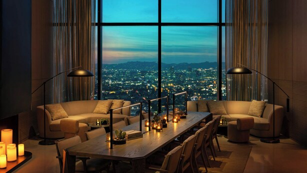 A modern dining area with a large table, two sofas, and a city view through floor-to-ceiling windows. - AC Hotel Downtown Los Angeles, a Marriott Hotel (Los Angeles)