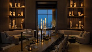 A modern living room with a long wooden table, sofas, and a large window with a city view. - AC Hotel Downtown Los Angeles, a Marriott Hotel (Los Angeles)