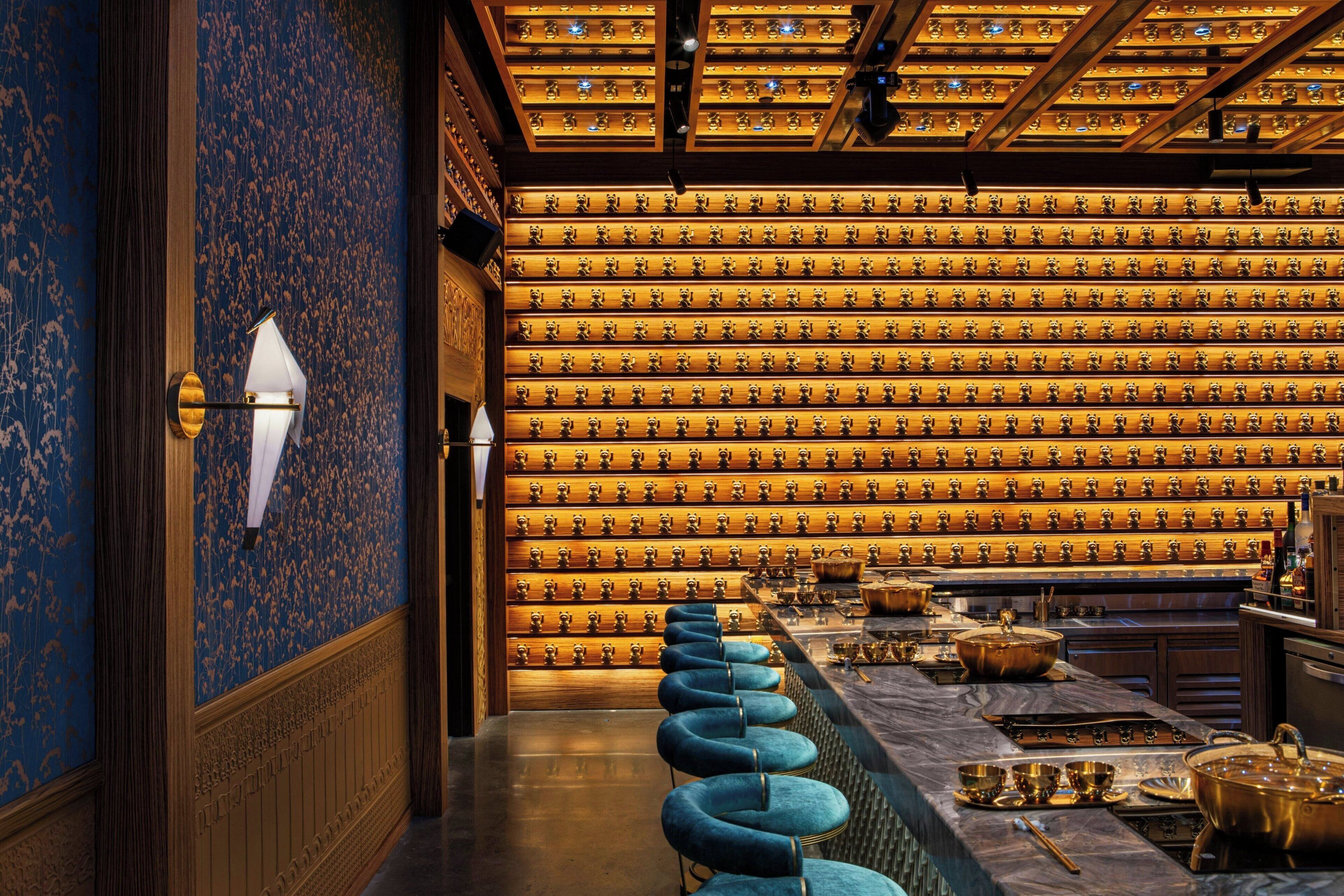 A bar area with a row of blue barstools, a wall of trophies, and a bar counter with various items.