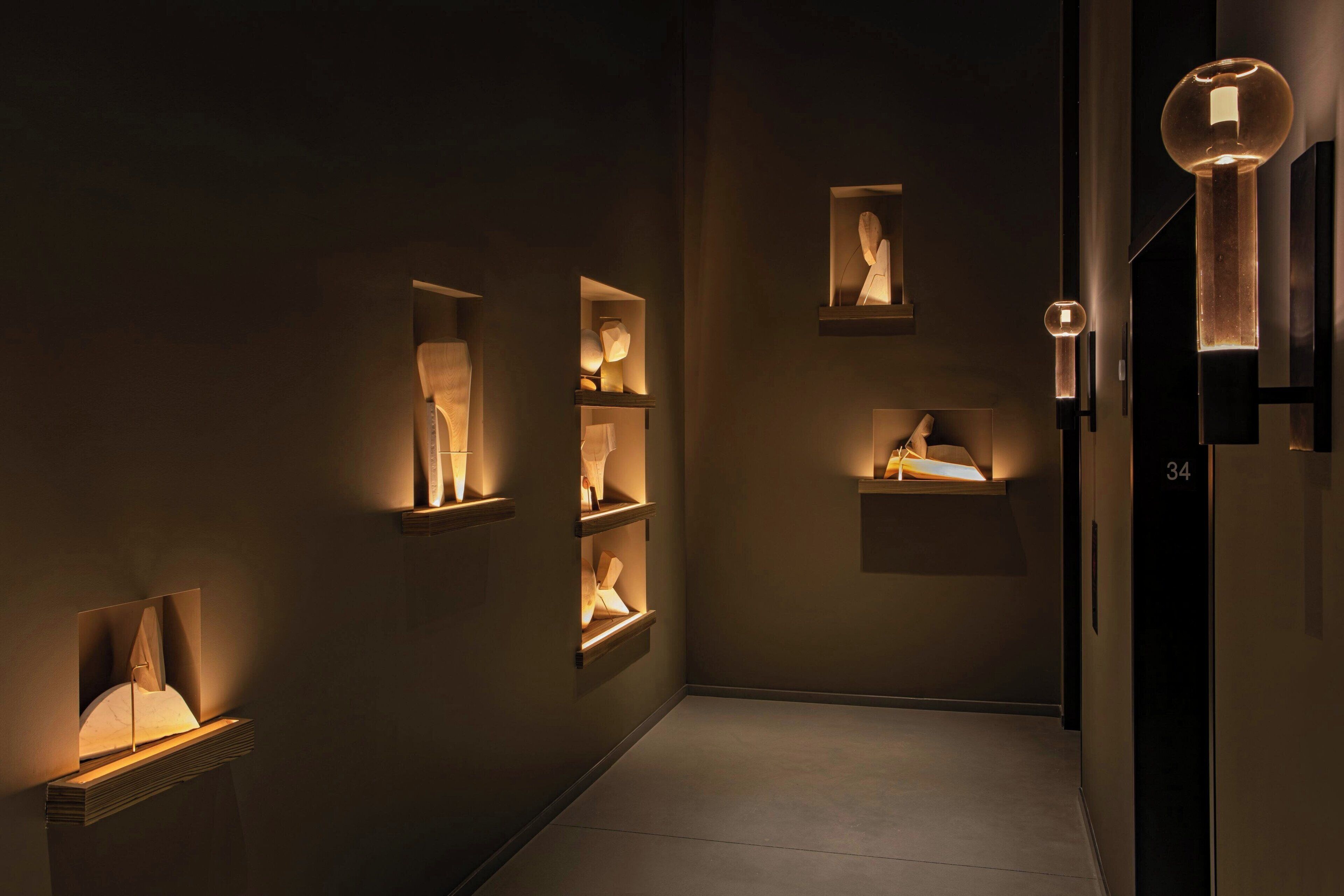 A hallway with recessed lighting and wall-mounted display cases containing sculptures.