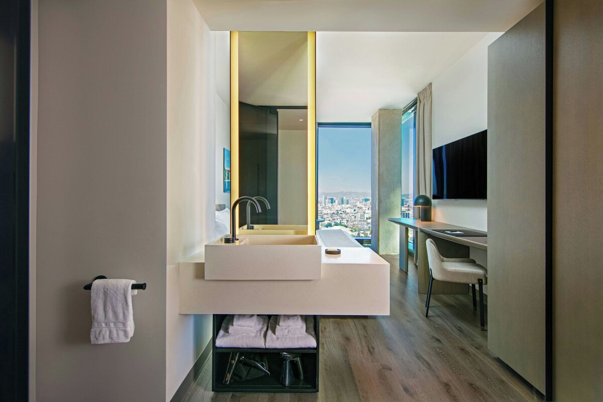 A modern bathroom with a large mirror, a sink, and a chair.