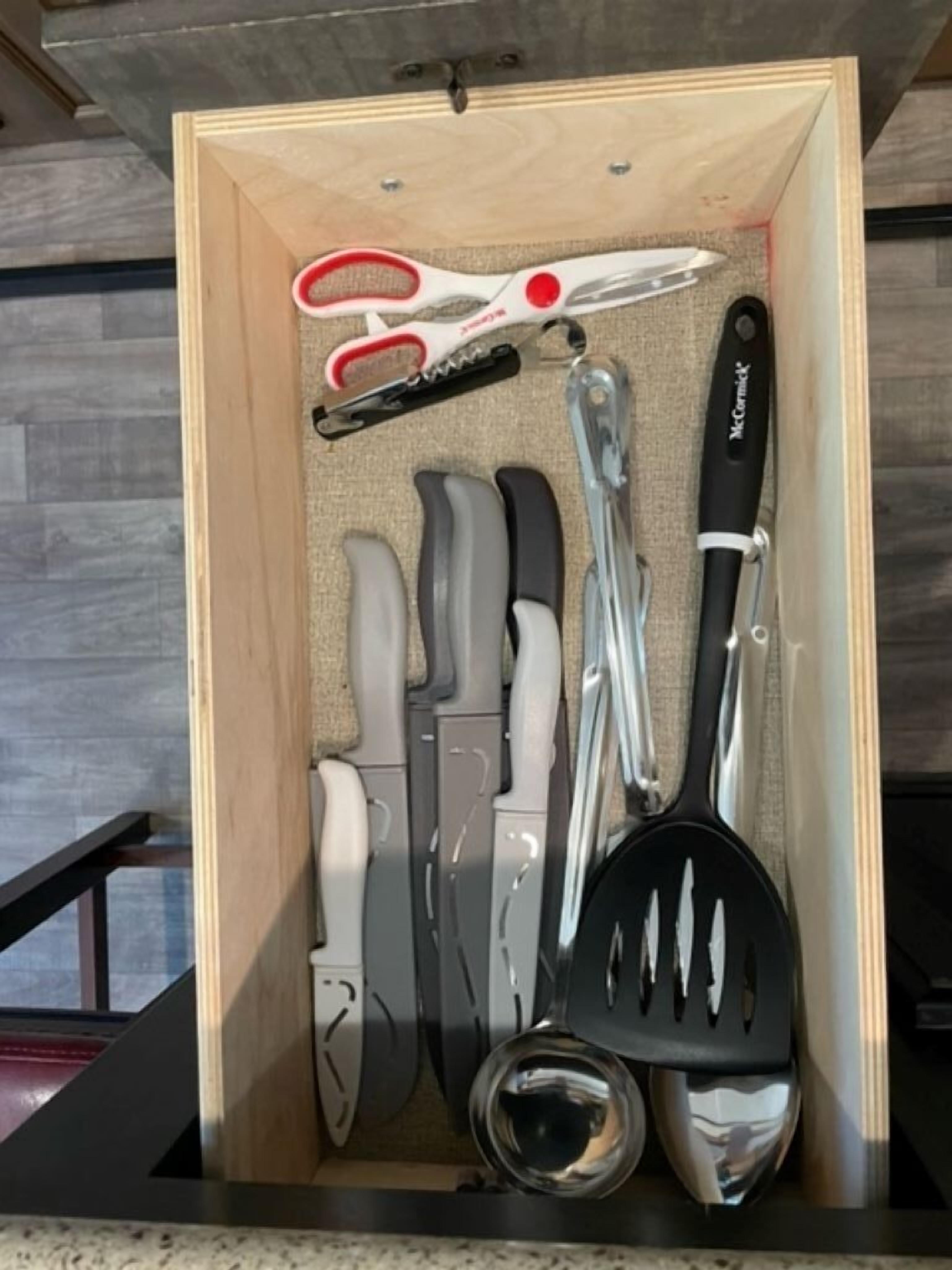 Un cajón con varios utensilios de cocina, como unas tijeras, una espátula y un juego de cuchillos.