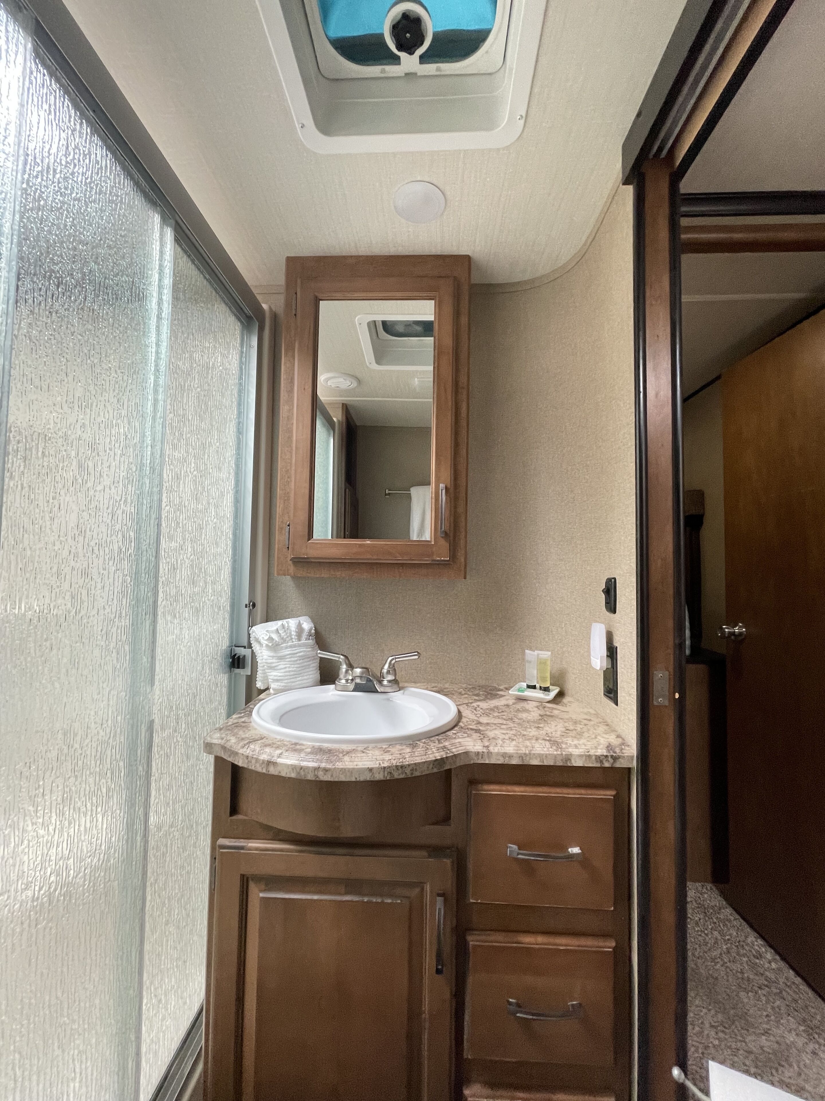 A bathroom with a sink, mirror, and wooden cabinets.