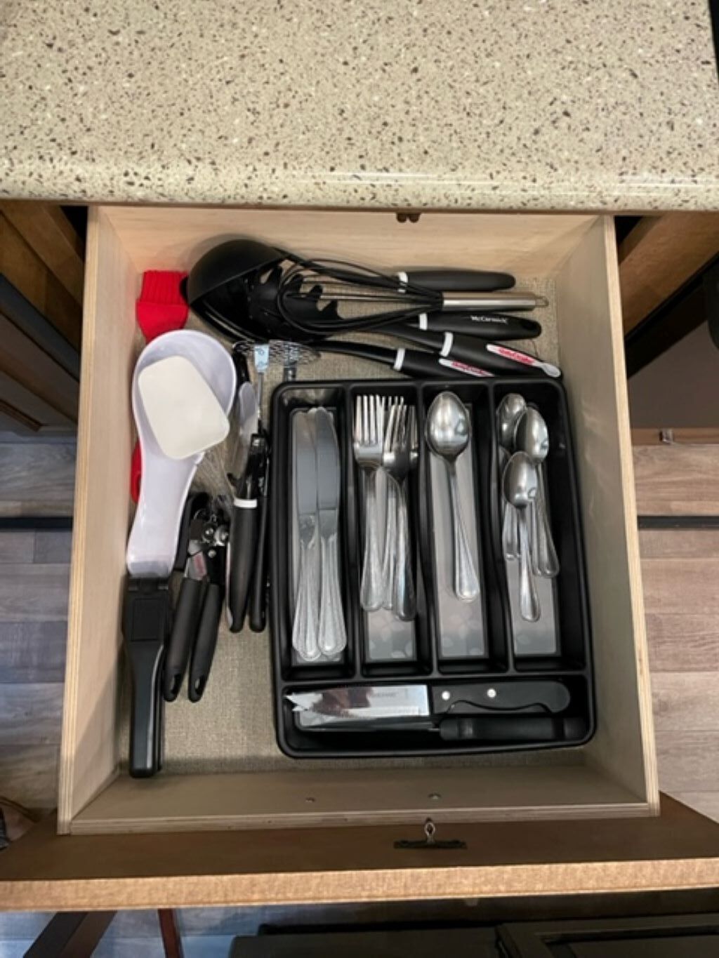 A drawer containing a set of silverware, including forks, knives, and spoons, neatly arranged in compartments.