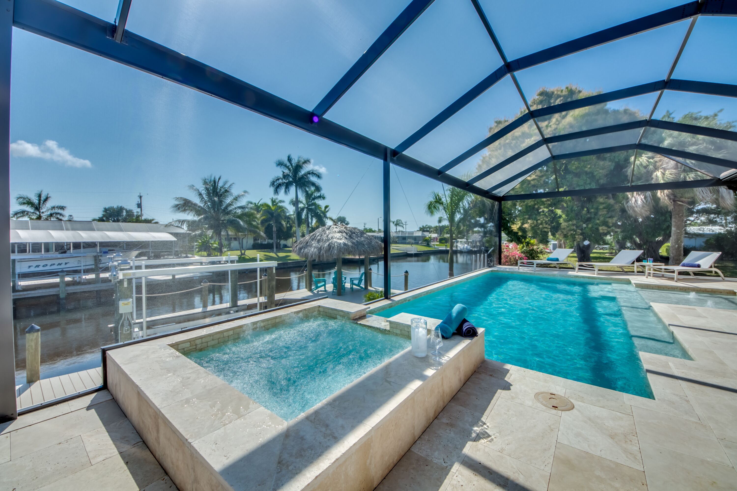 An indoor swimming pool with clear water, surrounded by lounge chairs and a glass enclosure.