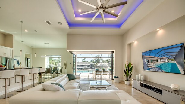 Amplia sala de estar con un sofá modular blanco grande, una mesa de comedor y una zona de cocina.