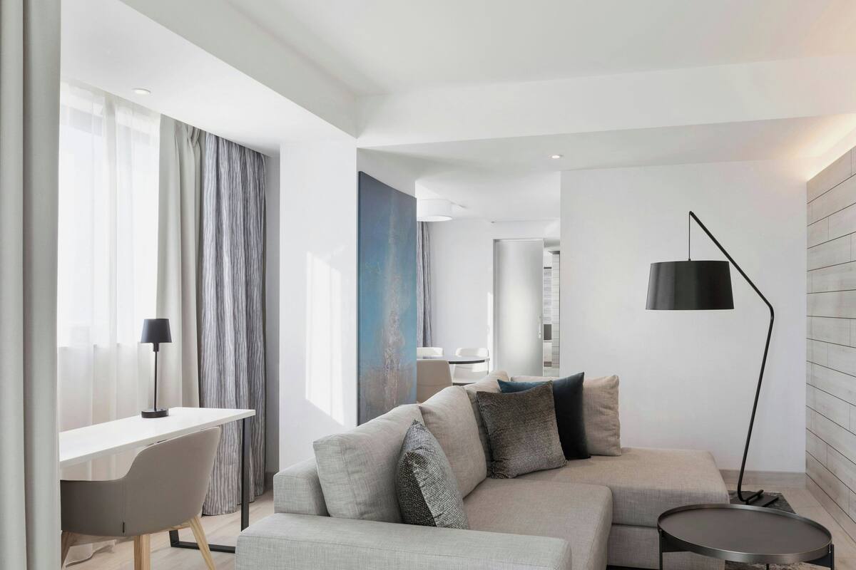 A modern living room with a sofa, a desk, and a lamp.