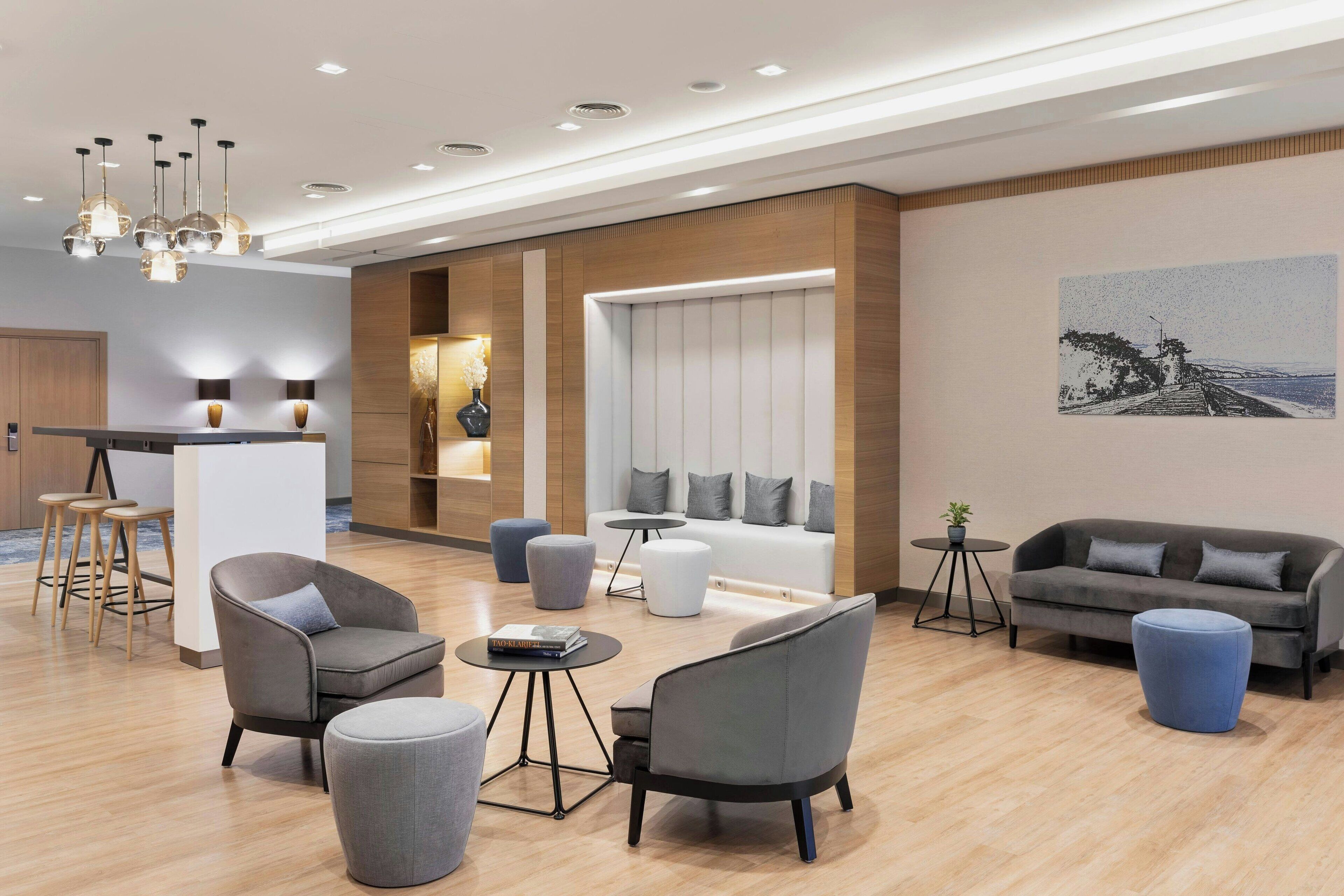 Ein modernes Wohnzimmer mit einer Couch, Sesseln, Poufs und einem Couchtisch.