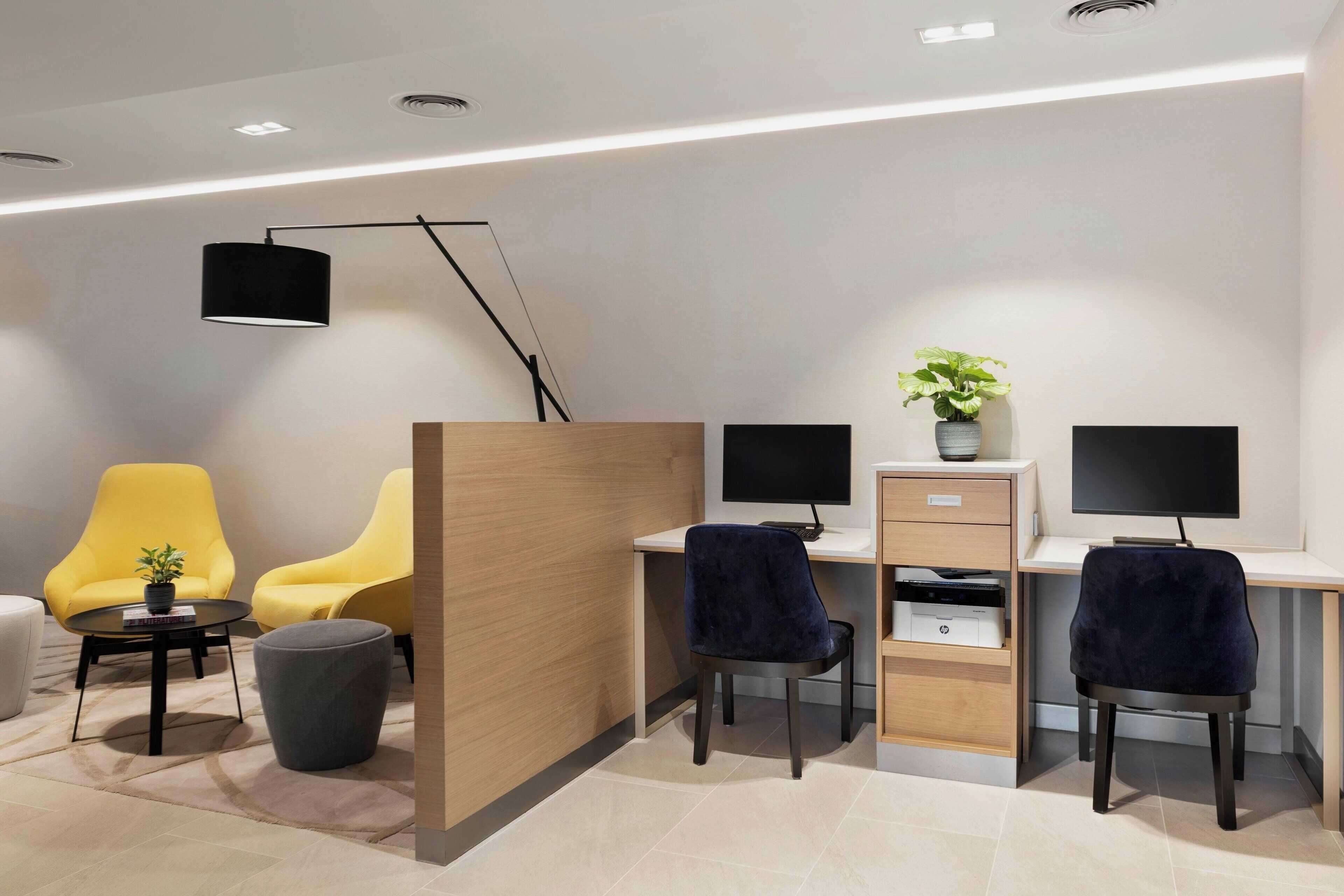 A modern office space with two desks, two chairs, a black floor lamp, and a potted plant.