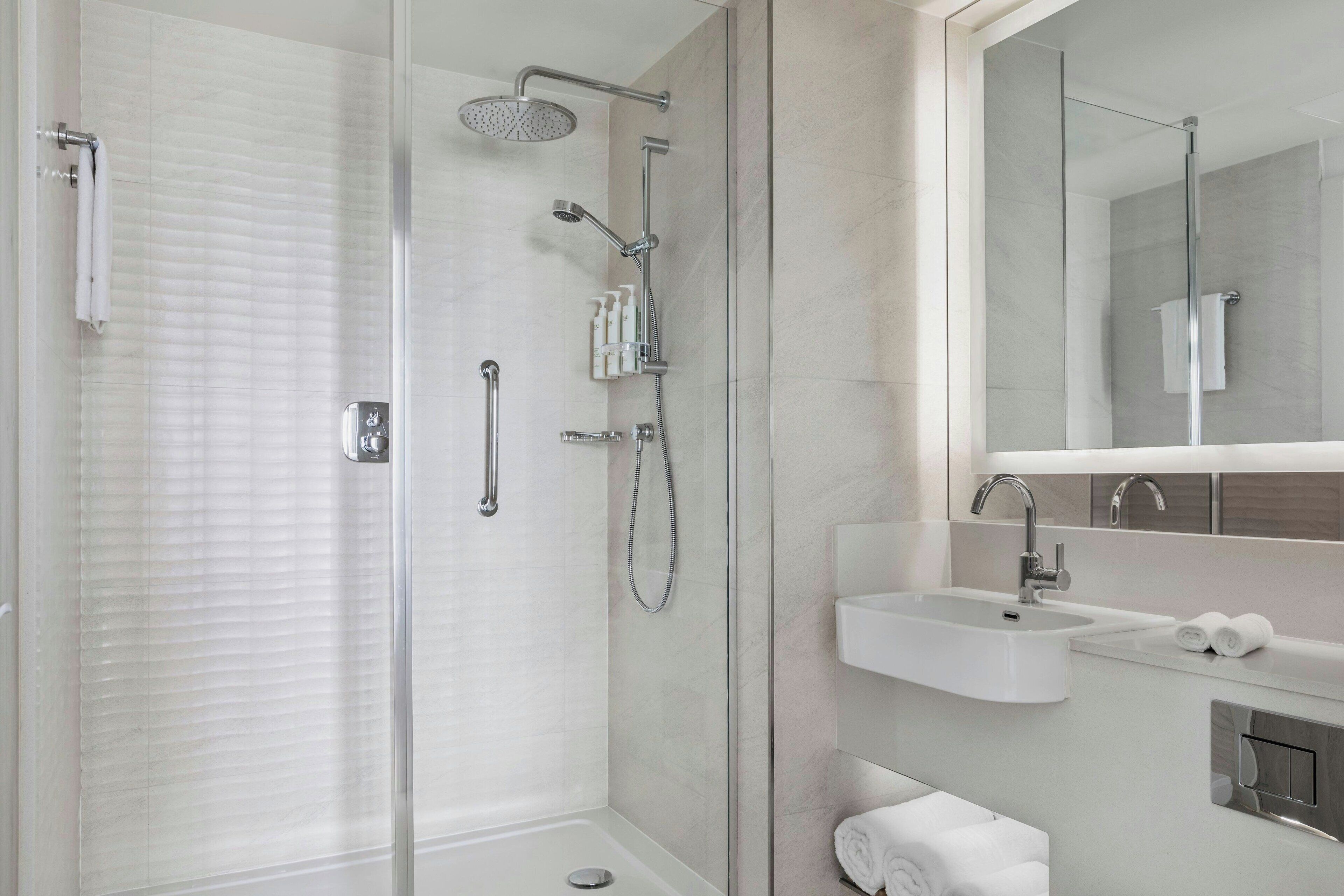 A modern bathroom with a glass-enclosed shower, a sink, and a mirror.