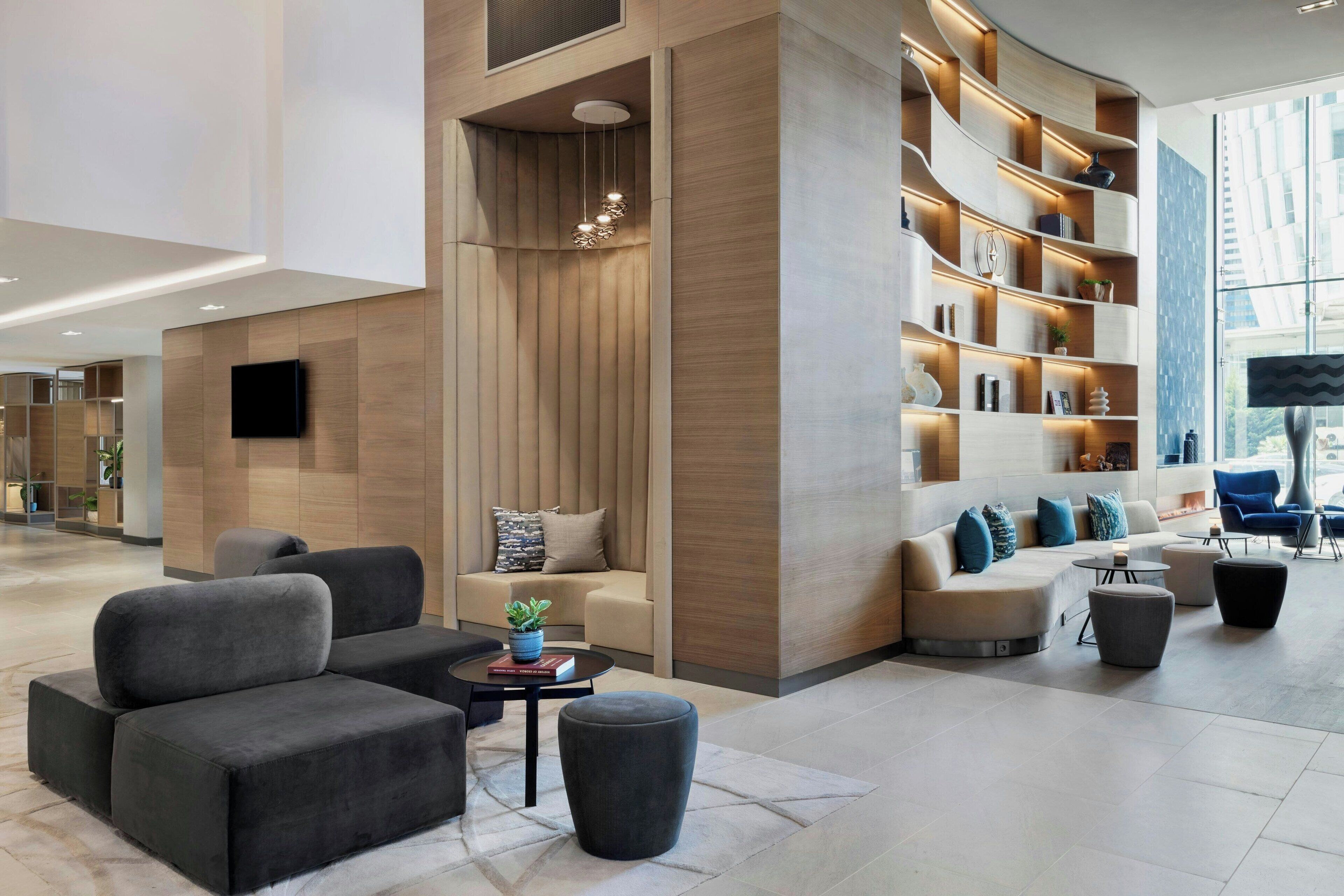 A modern lobby with a sectional sofa, a coffee table, and a bookshelf.