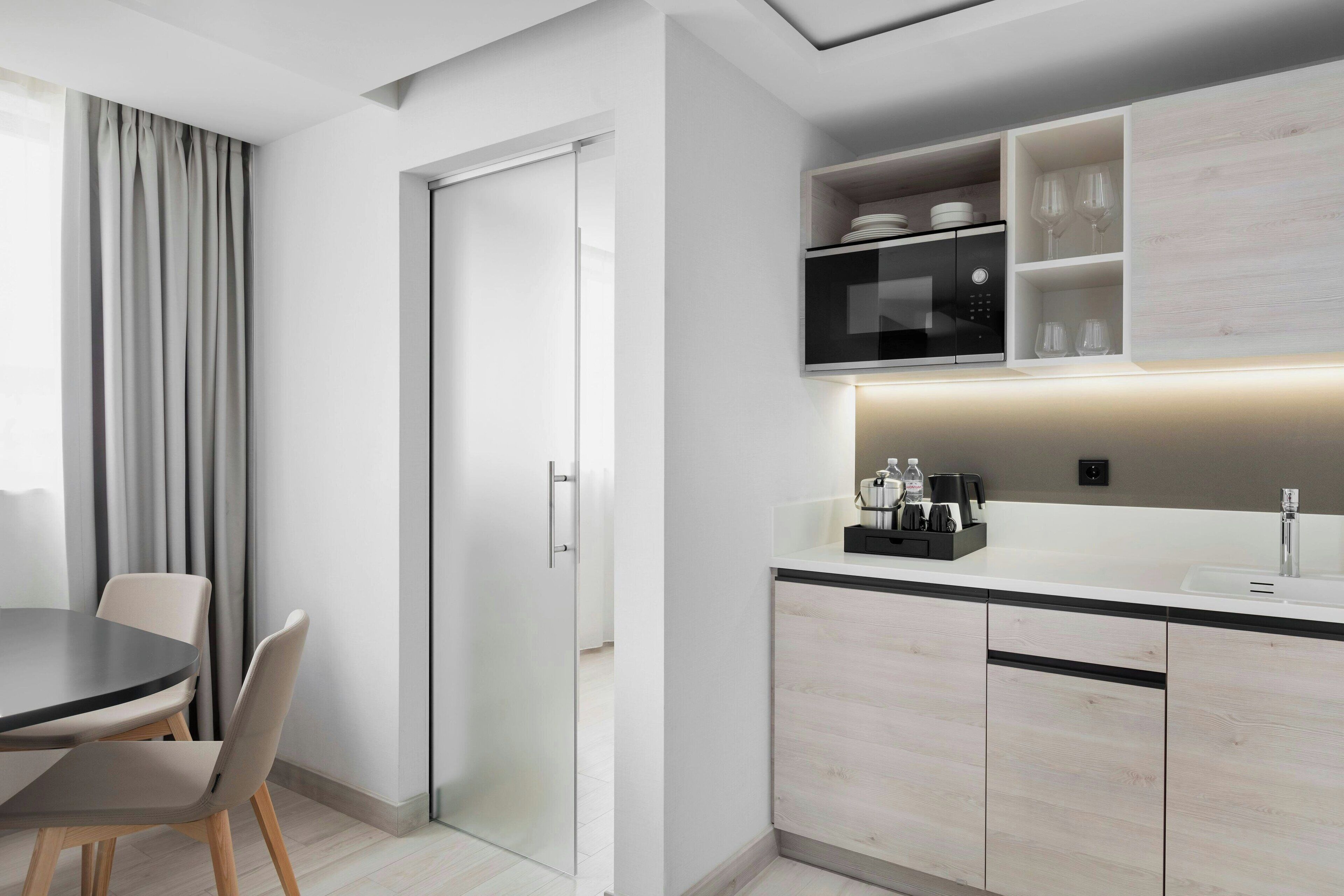 A modern kitchen with a built-in microwave, a sink, and a countertop with a coffee maker.